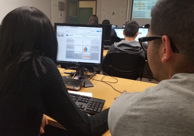 Two students are looking at a poster template on a computer screen.
